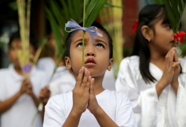 A Filipino boy participates during Palm Sunday rites outside the Holy Family Parish Church in Quezon city, north of Manila, Philippines on Sunday, April 13, 2014. Palm Sunday marks the triumphant entry of Jesus Christ into Jerusalem and ushers in the Holy Week observance among Catholics worldwide. (AP Photo/Aaron Favila)